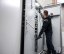 Osoba v bezpečnostním vybavení testuje elektrický panel pomocí zkoušečky napětí. Osoba v bezpečnostním vybavení testuje elektrický panel pomocí zkoušečky napětí.